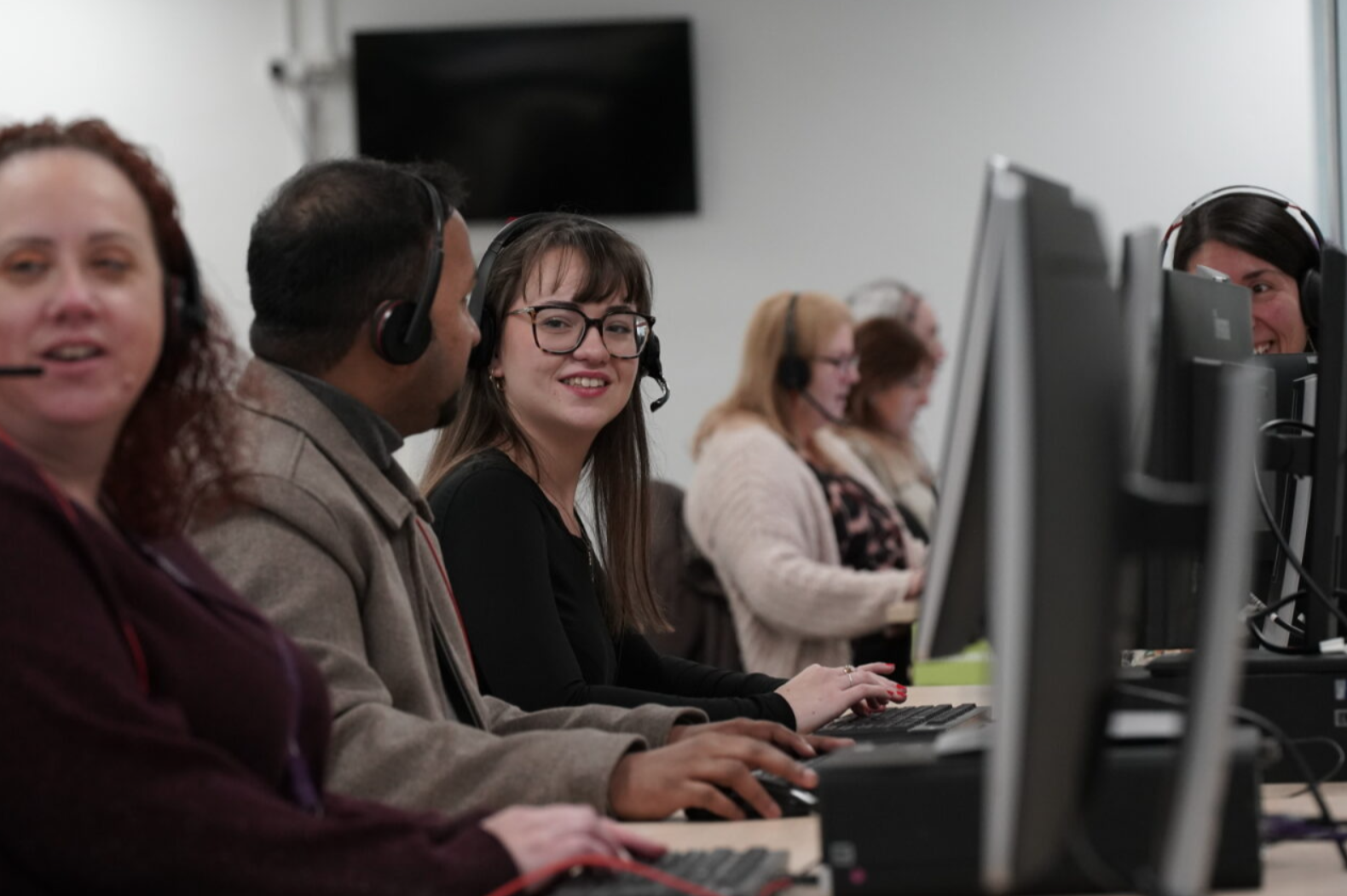 A group of people sitting at computersAI-generated content may be incorrect.